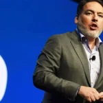Ο Shawn Layden μπροστά από το λογότυπο του PlayStation με φόντο δημοφιλή αποκλειστικά παιχνίδια