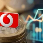 Κάρτα SIM της Vodafone πάνω σε κέρματα του ενός ευρώ και θολωμένο φόντο με γράφημα δεδομένων κινητής.